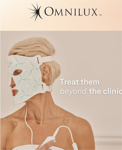 Woman wearing the Medical Grade OMNILUX CONTOUR face mask, with the control in her hand and attached to the mask.