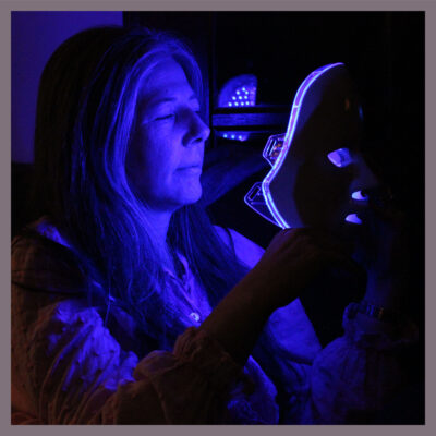 Woman setting the blue light on her WHITE MASK. 415+nm blue light specifically reduces Acne Vulgaris by helping deplete bacterial and reduce sebum production and reducing shine for a clearer smoother skin.