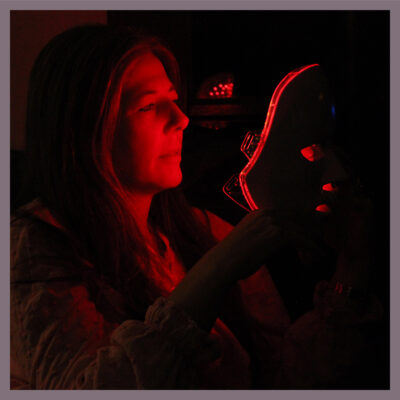 Woman setting the red light on her WHITE MASK. 633nm red rejuvenates skin that is showing lines. This red light will increase collagen production by the skin cells reacting to the lightwave of 633nm, delivering a smoother skin texture